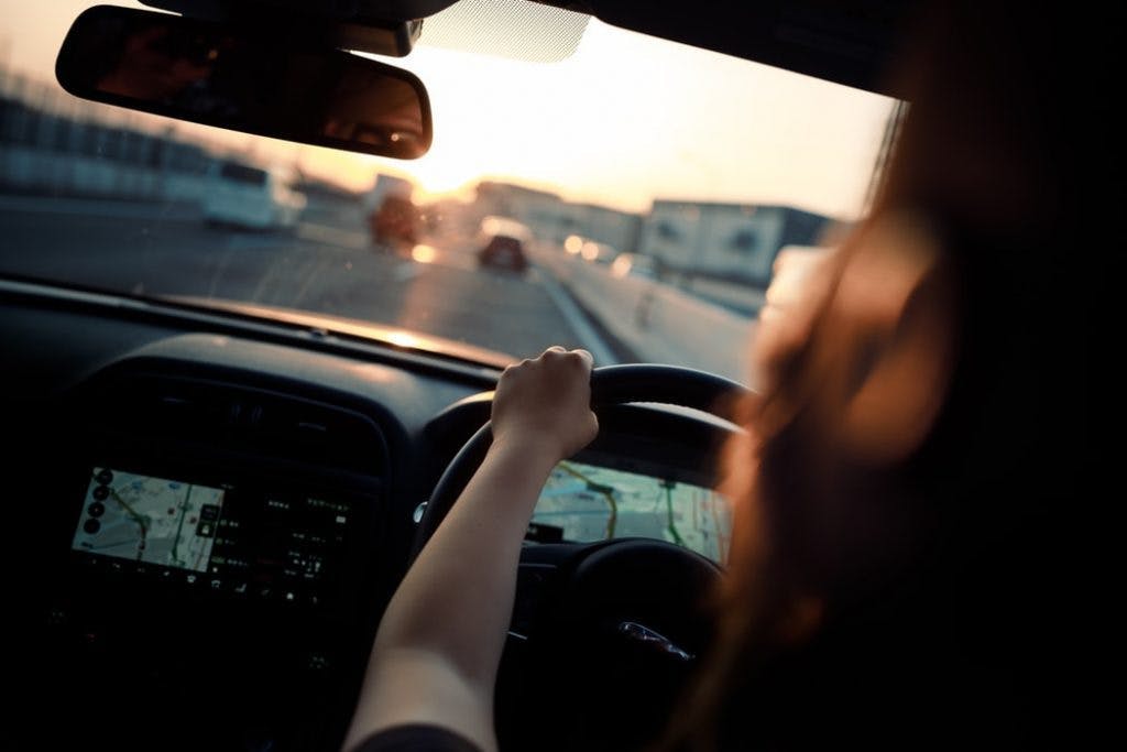 image of a driver with both hands on steering wheel and looking at the road ahead