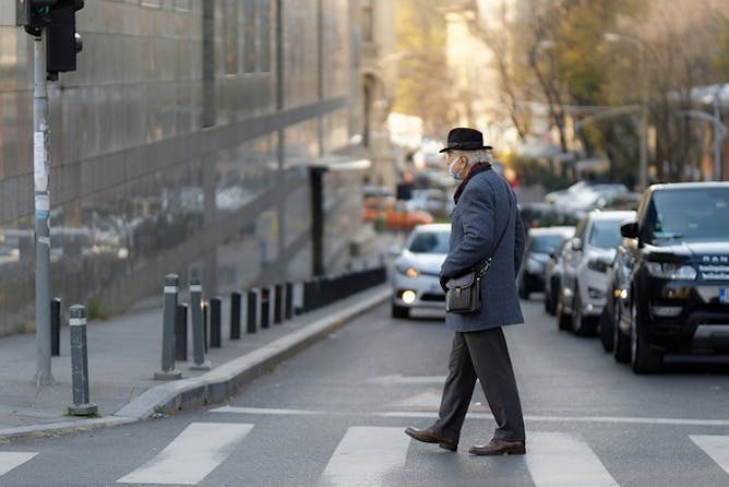 Elderly man walks across a zebra crossing