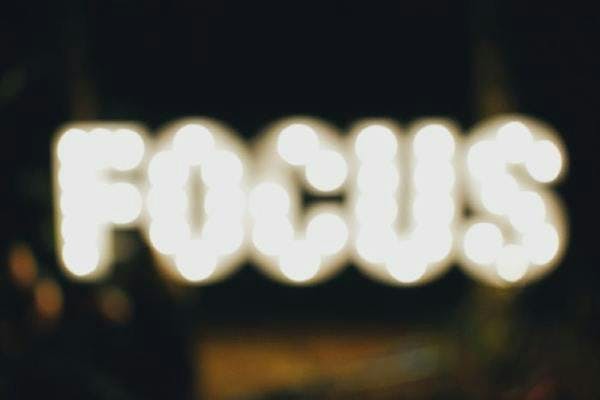 An out-of-focus image of a sign made out of bulbs. The sign, ironically, reads 'Focus'.