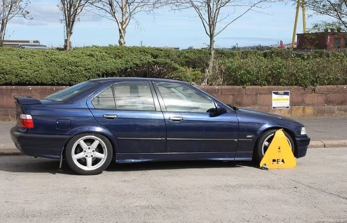 A dark blue car with its wheels clamped