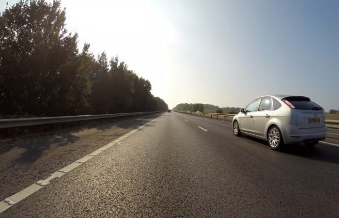 A sliver car driving on a road after having vehicle tax