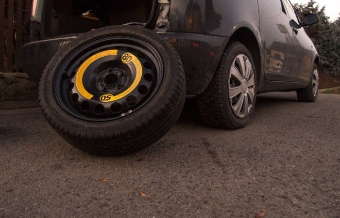 Photograph of a spare tyre leaning up against the rear bumper of a car