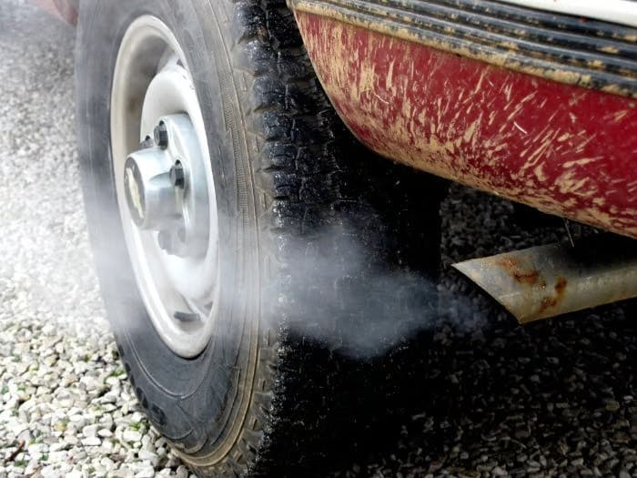 An image of a back car tyre and the car exhaust 