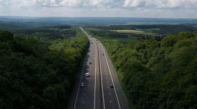 An image of a motorway surrounded by a forest