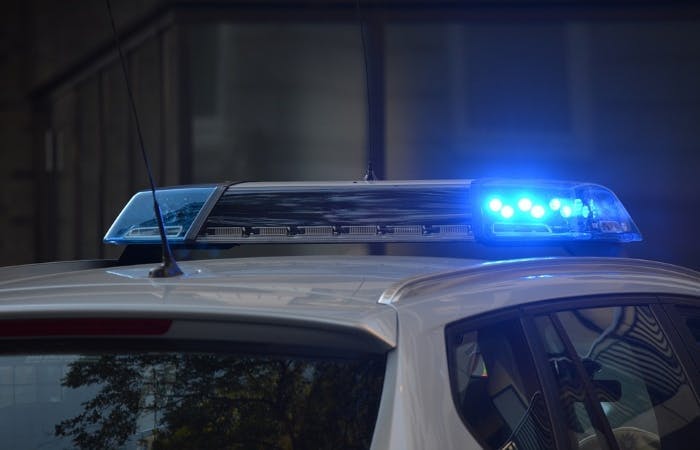 An image of the top of a police car with the blue light on 