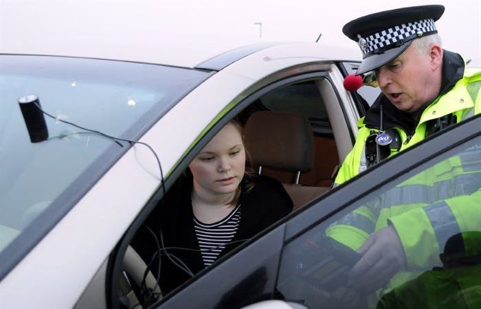 An mage of a policeman talking to a young woman in a car 