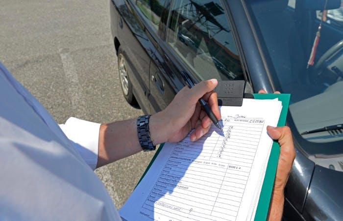 An image of a person filling in details in a paper form on a clipboard 