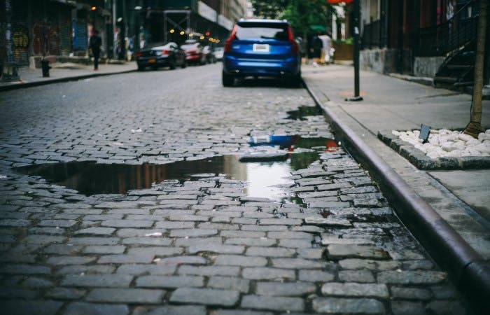 An image of a cobalt street with a blue car parked on it 
