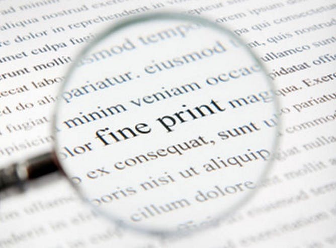 A magnifying glass held over a piece of paper with lorem ipsum written on it. The words in the centre of the magnifying glass read 'fine print'.