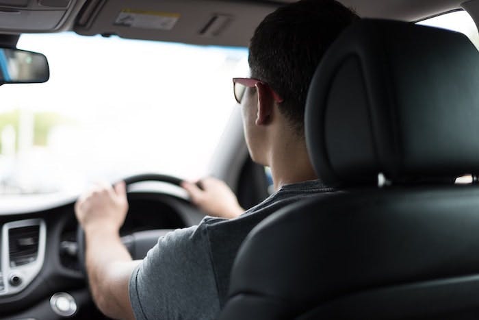 A man driving with hands on the steering wheel during his driving test