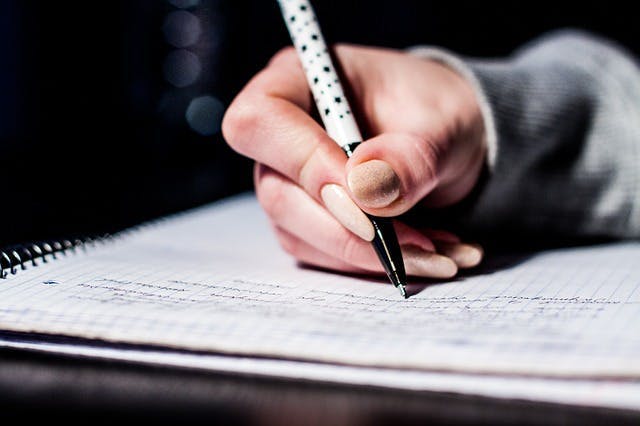 Hand holding a pen and writing theory test revision tips