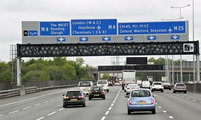 Cars driving on a motorway with motorway direction signs above