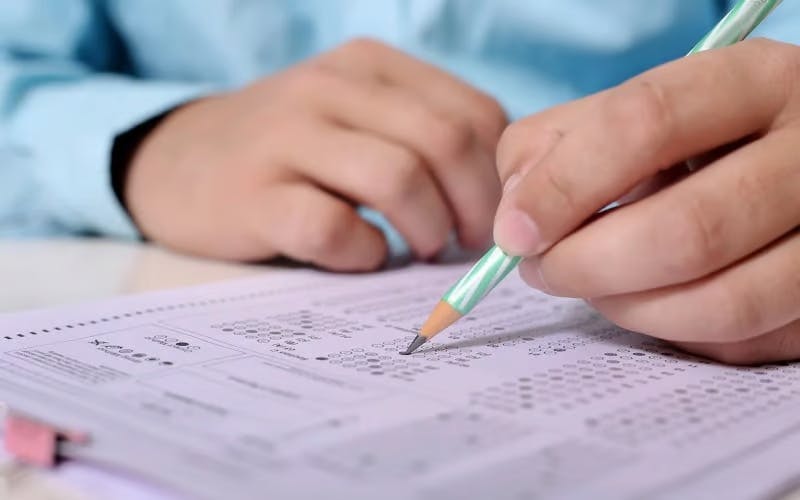 Person filling in a test with a pencil, representing the theory test