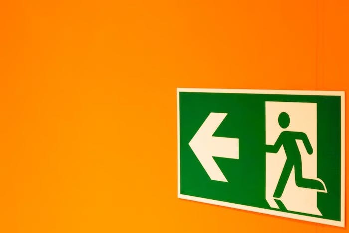 An emergency exit sign against an orange wall