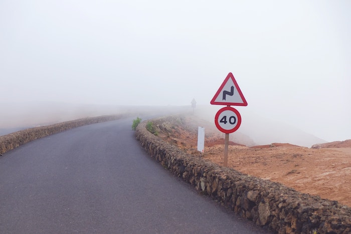Speed limit sign on foggy rural road