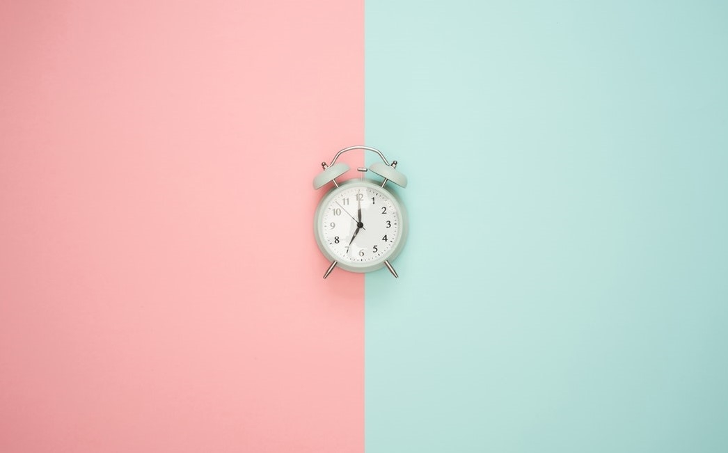 Alarm clock set against pink and green background