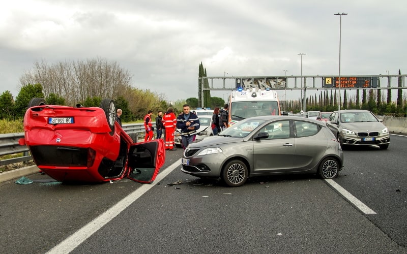 Car accident on a motorway, with one car overturned, with emergency responders in the background