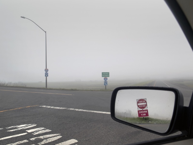Foggy road with car mirror showing a reflection of a no entry sign