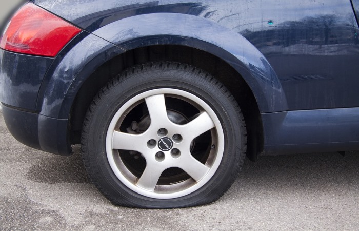 A dark blue car with a flat tyre
