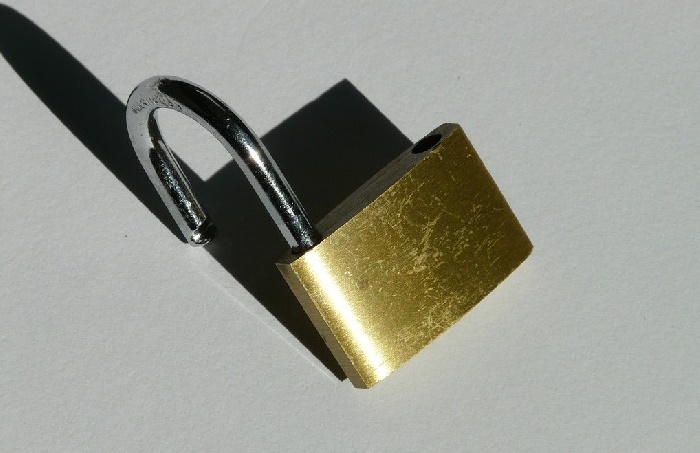Open gold padlock leaning on grey surface