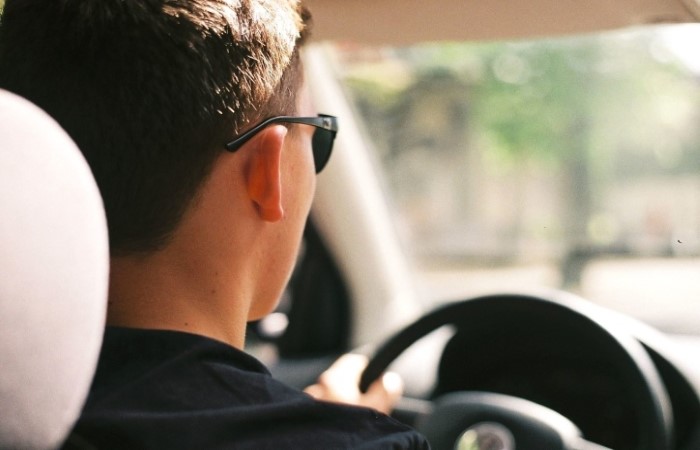 A man driving his car and wearing sunglasses