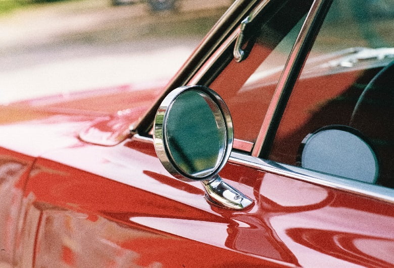 A picture of a red car's side mirror.