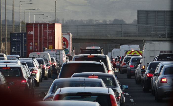Three lanes of cars in a traffic jam facing bridge