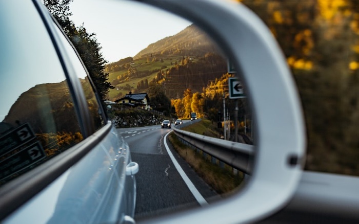 View of other cars on country road from a wing mirror